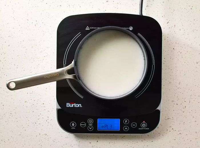 A saucepan on the stove with rice, coconut milk, and water being cooked