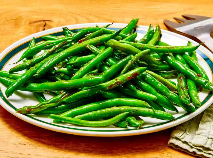 A close-up, low-angle shot of a pile of sautéed, garden-fresh green beans on a serving platter.