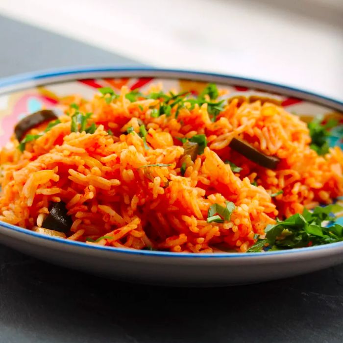 Close-up shot of Mexican rice topped with fresh herbs in a bowl.