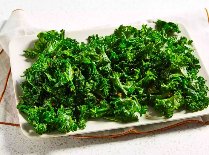 A mid-angle view of a white platter filled with garlic kale.