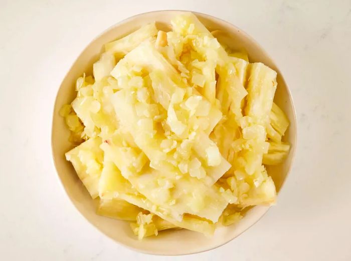 A top-down view of cooked yuca topped with a lemon garlic onion sauce, served on a plate