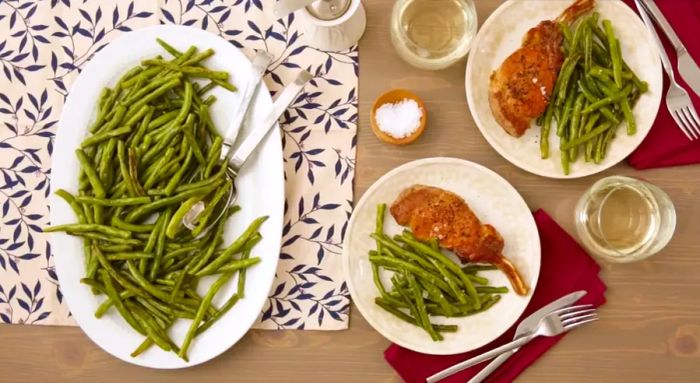 Roasted green beans served alongside chicken breasts on a plate