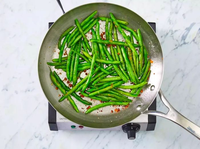 Green beans being cooked in a skillet.