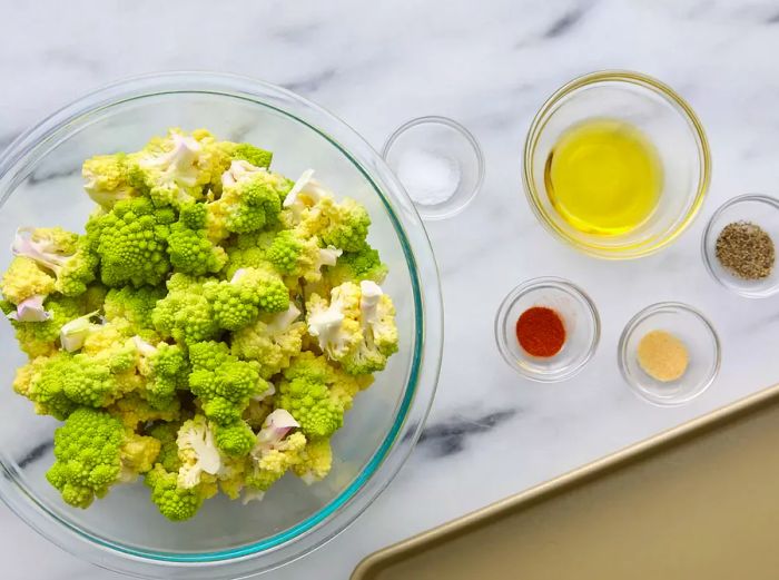 A top-down view of roasted Romanesco ingredients arranged in various glass bowls.