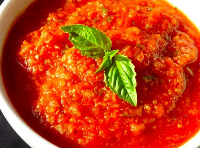 A bowl of homemade tomato sauce garnished with fresh basil leaves