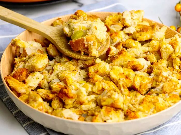 A close-up view of a spoonful of old-fashioned stuffing being lifted from the baking dish.