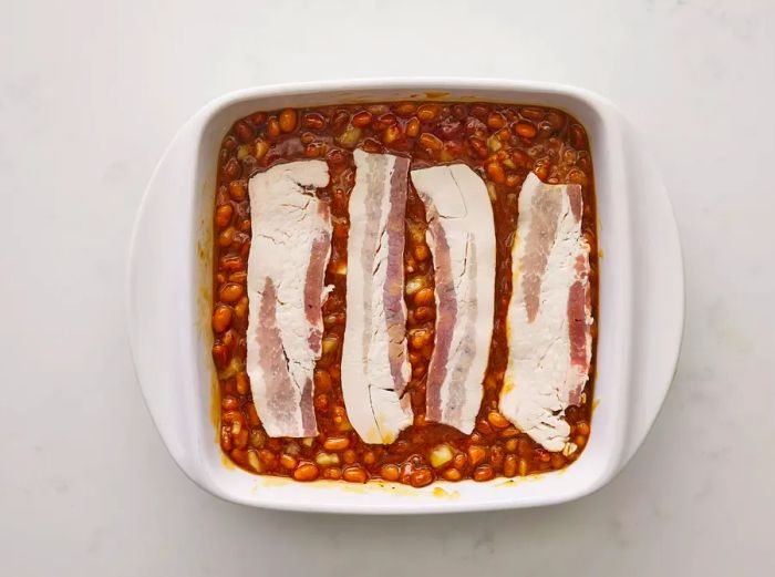 Place sliced bacon over the bean mixture.