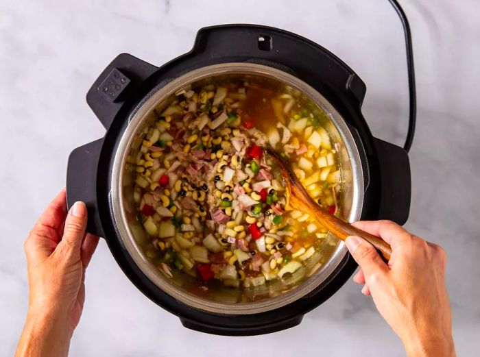 Bird's-eye view of black-eyed peas cooking and blending together in a slow cooker.