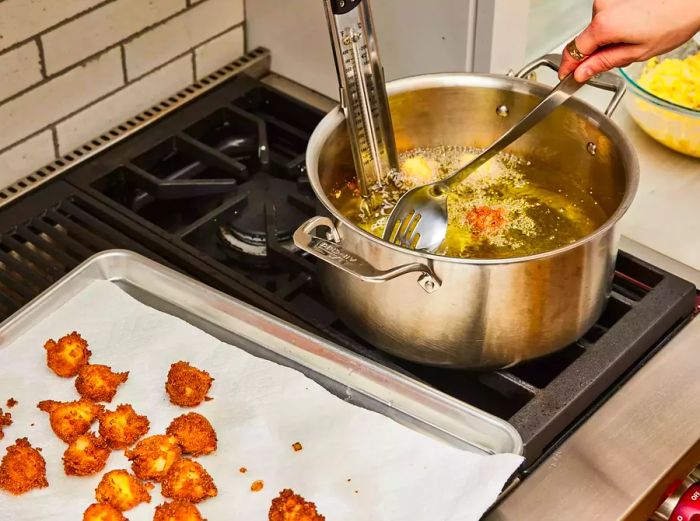 Spoonfuls of batter frying in hot oil, then placed on a paper towel to drain after cooking.