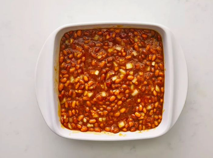 Combine canned beans, brown sugar, onion, ketchup, mustard, Worcestershire sauce, and seasonings in a baking dish.