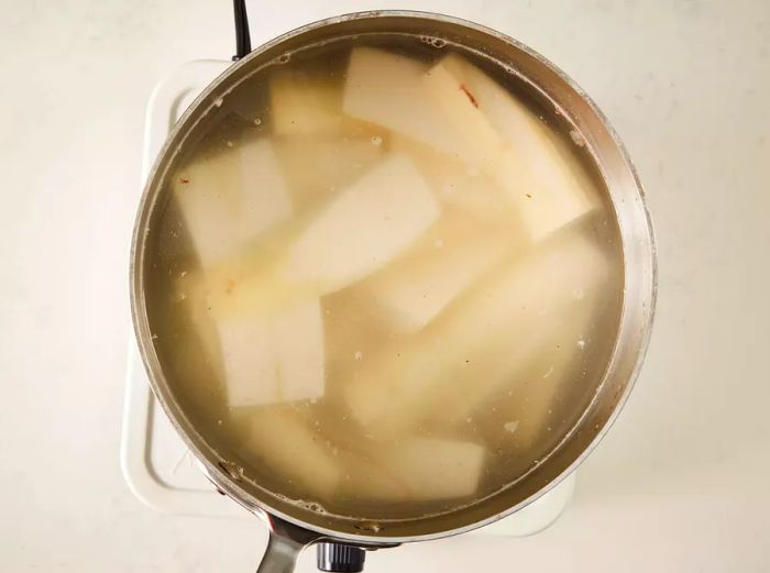 A top-down view of yuca submerged in water in a pot