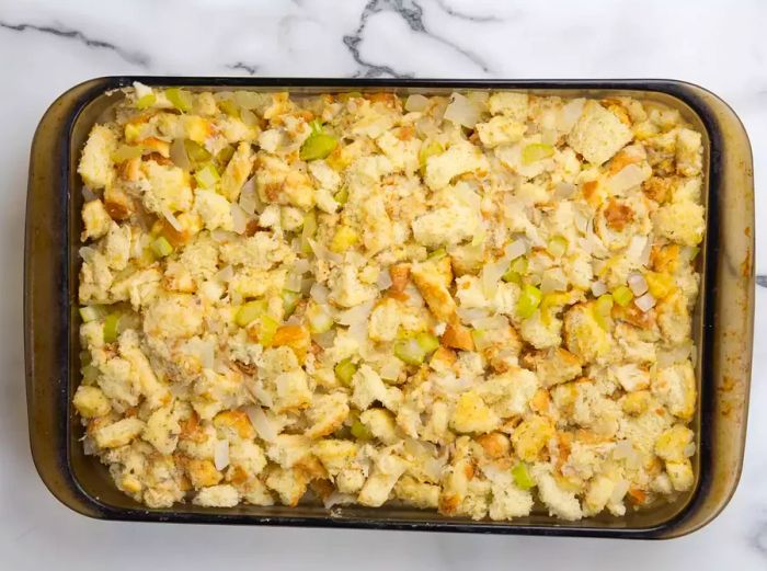 A top-down view of the stuffing mixture pressed into a baking dish, ready to go into the oven.