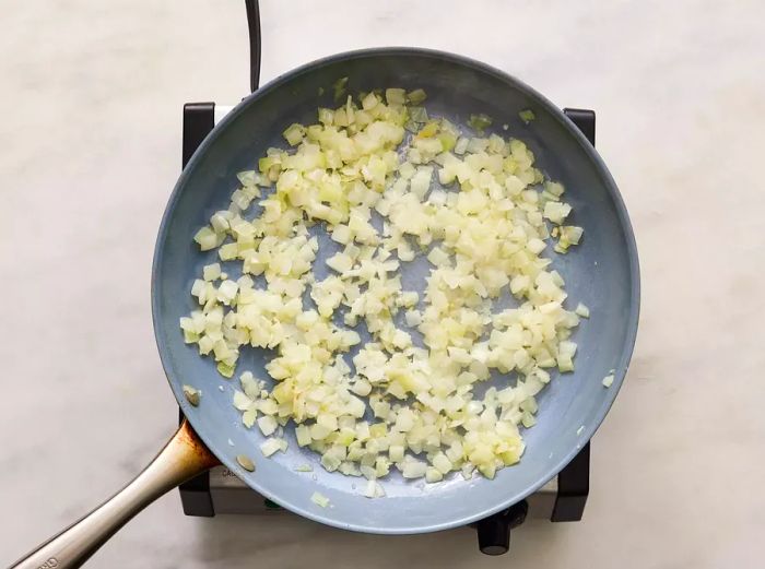 Onion and garlic sautéing in a skillet with oil.