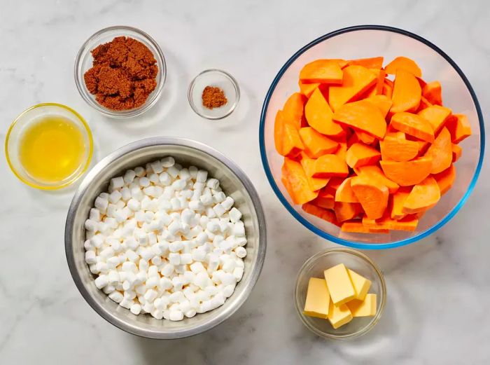 Various bowls filled with ingredients to prepare the sweet potato casserole with marshmallows.