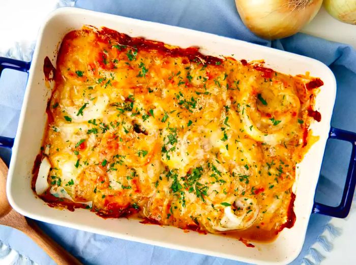 An overhead shot of a white casserole dish filled with cheesy, baked onions