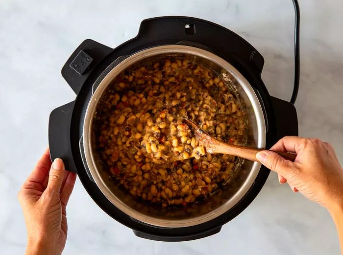 Aerial shot of cooked black-eyed peas being scooped from the slow cooker.