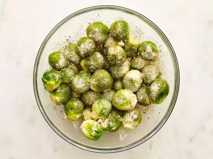 Brussels sprouts coated in seasoning in a bowl