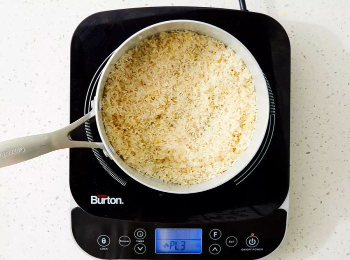 Rice being added to a saucepan with onions and butter.