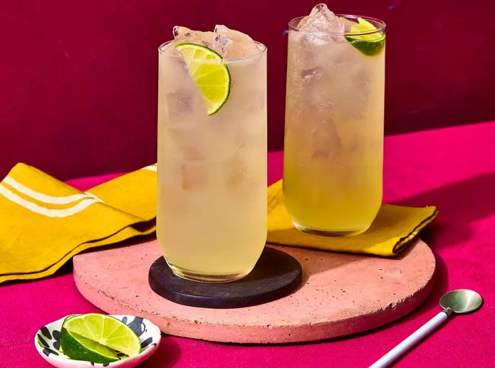 Two Moscow Mule cocktails placed on a pink stone surface.