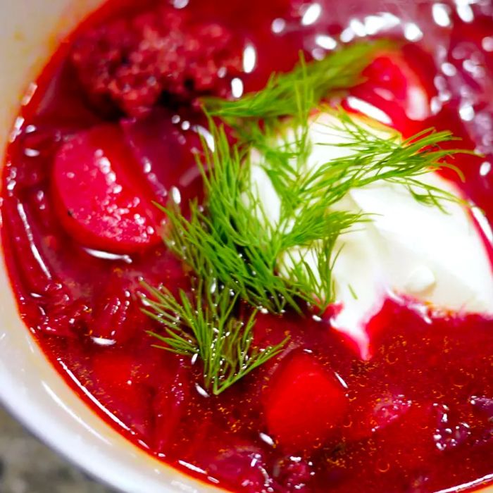 A hearty bowl of beet soup, garnished with sour cream and dill