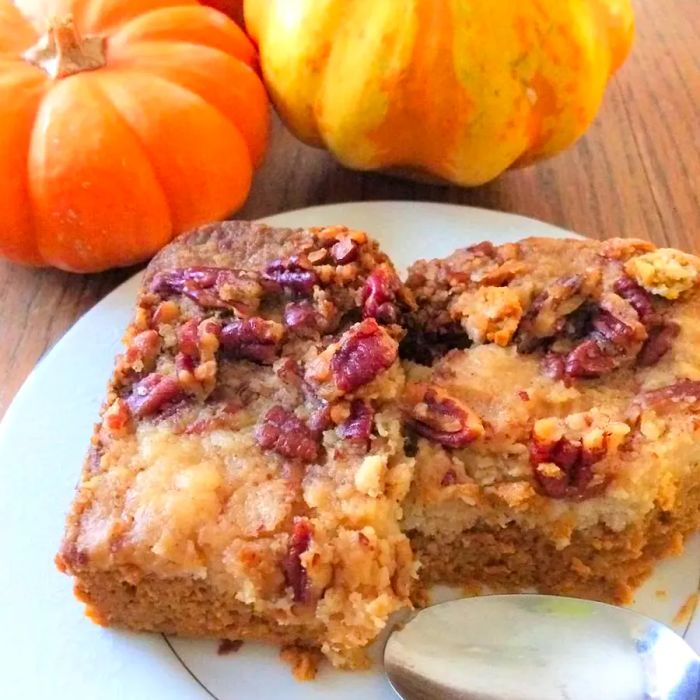 Upside Down Pumpkin Cake served on a white plate with pumpkins in the background