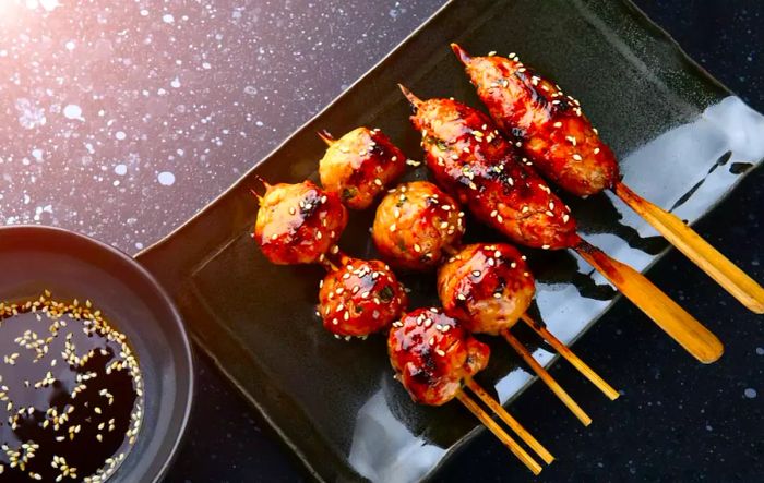 A delicious Japanese meatball skewer, or tsukune, grilled and glazed with teriyaki sauce, ready to be enjoyed under studio lighting.