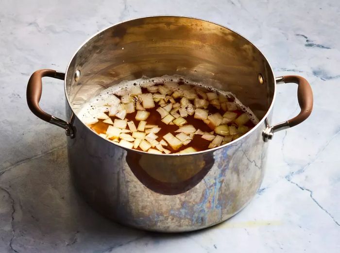 A high-angle view of beer brat broth simmering in a stockpot.