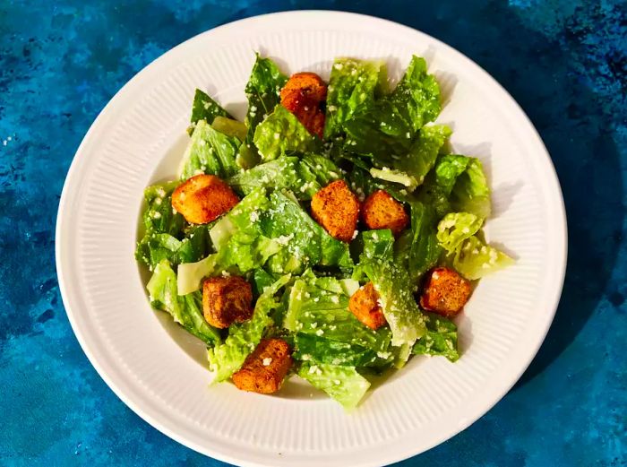 A top-down view of a classic restaurant-style Caesar salad served on a plate.