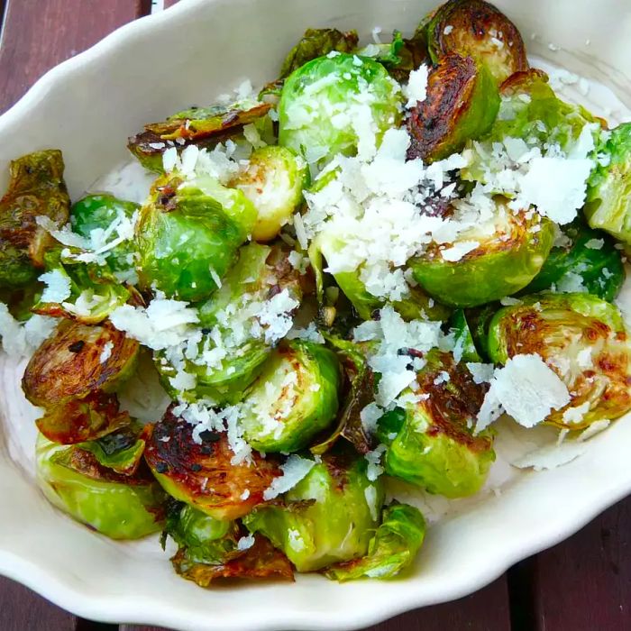 A serving of Parmesan Brussels sprouts beautifully plated in a white dish.