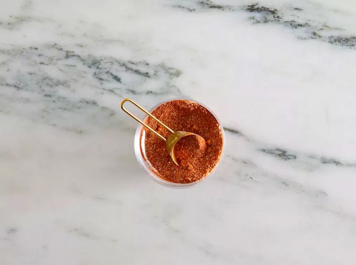 Aerial view of brown sugar, paprika, chili powder, salt, and garlic powder in a mixing bowl.