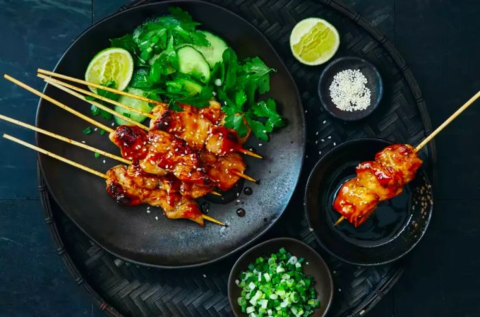 Japanese yakitori skewers with chicken and vegetables, served alongside a fresh salad, captured on a dark background.