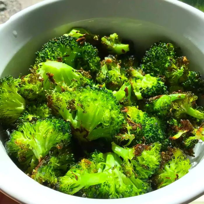 A close-up of Roasted Garlic Lemon Broccoli served in a white bowl.