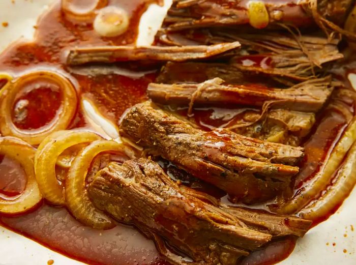 A close-up view of sliced beef brisket with onions, soaking in the flavorful juices.