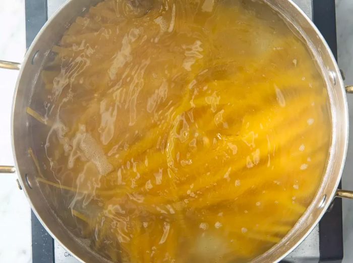 An overhead shot of pasta noodles boiling in a large pot.