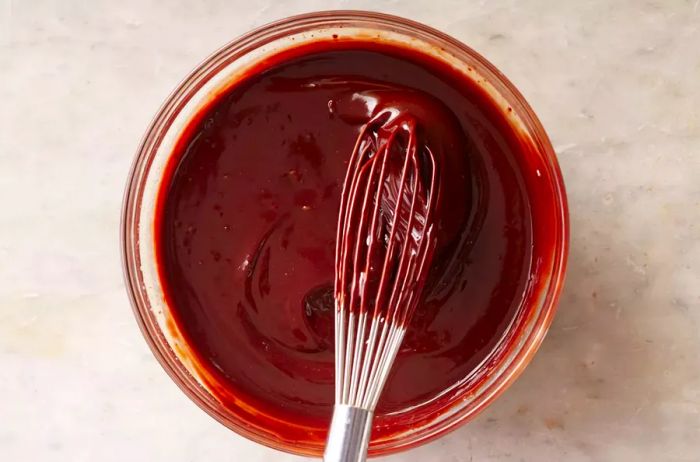 Melted chocolate in a glass bowl, whisked together with a wire whisk