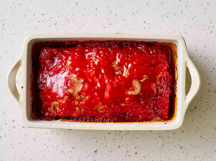 A loaf pan filled with a perfectly baked brown sugar meatloaf, topped with a glossy ketchup glaze.