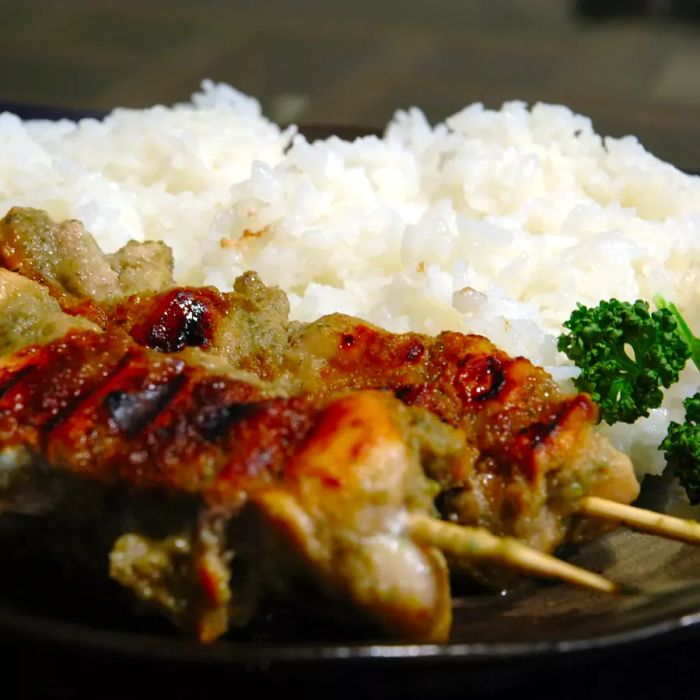 Close-up shot of Jamaican Jerk Chicken on skewers served with white rice