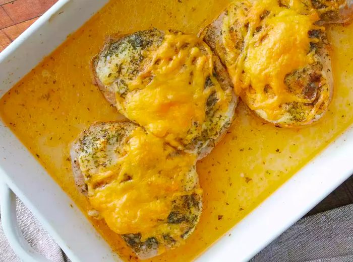 A top view of pork chops in a baking dish, covered with cheese