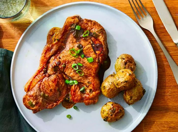 A plate of pork steaks paired with potatoes on a gray dish