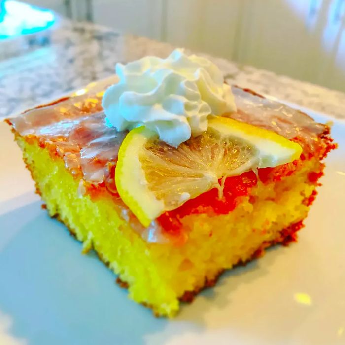 A high-angle view of a slice of lemon poke cake on a plate