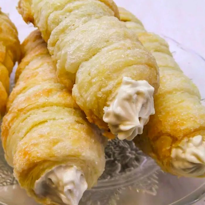 A close-up of cream horns made from puff pastry and filled with sweetened cream cheese