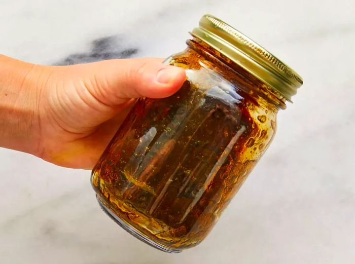 Hand shaking a jar containing oil, balsamic vinegar, salt, and pepper for the Tomato Mozzarella Salad recipe