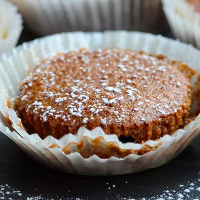 Pumpkin cheesecake cupcakes dusted with powdered sugar in a cupcake liner