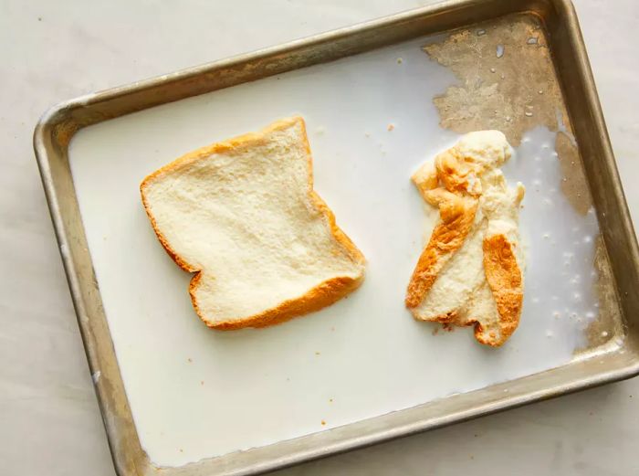 Two slices of bread soaking in milk on a baking sheet