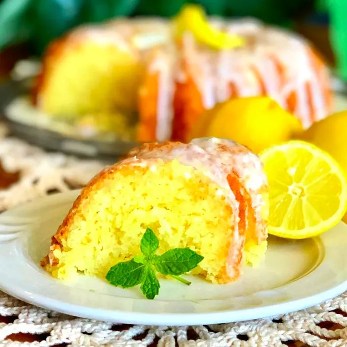 A mid-angle view of a slice of lemon ricotta cake with the rest of the cake behind it