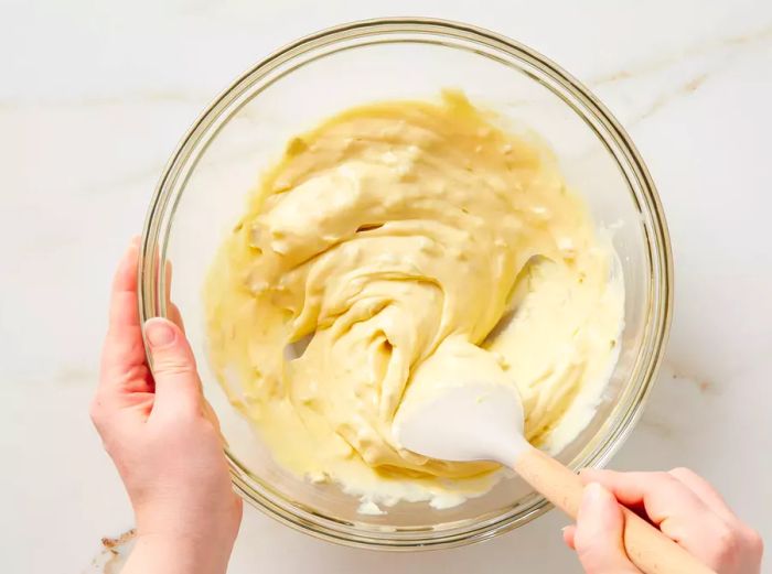 A spatula stirring together condensed cream of chicken and cream of celery soup in a glass bowl