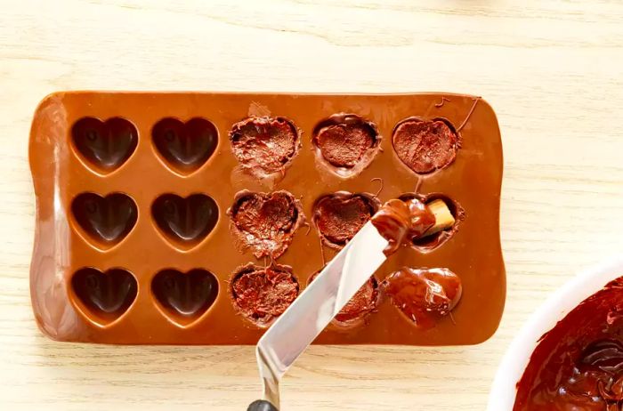 adding the final layer of melted chocolate over the filled molds