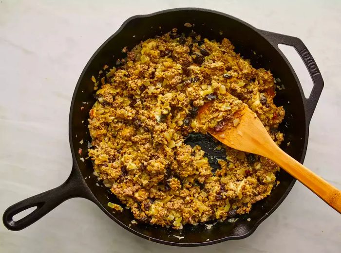 Raisins, chutney, curry powder, apricot jam, salt, and black pepper stirred into the ground beef mixture