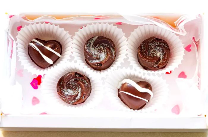 homemade filled chocolates placed in paper candy cups and packed into a box, perfect for Valentine's Day gifting