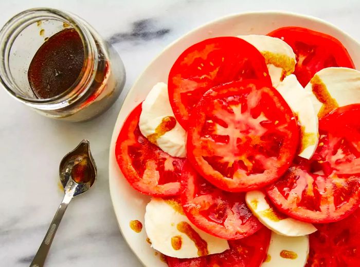 Aerial view of the Tomato Mozzarella Salad on a platter with dressing drizzled on top and basil sprinkled over